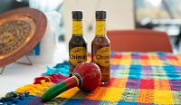 Hot sauce bottles and maracas on a colourful tablecloth