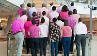 Groupe de personnes habillées en rose faisant dos à la caméra
