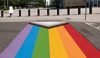 The inclusive Pride flag painted on a crosswalk outside